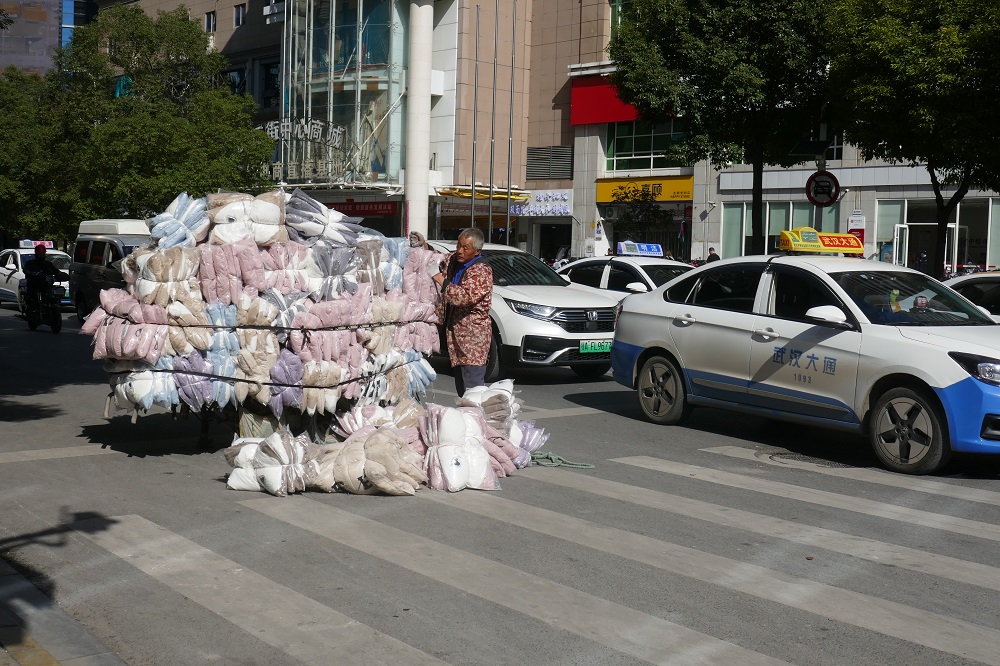 Lieferant in China mit vielen Paketen auf dem Wagen.
